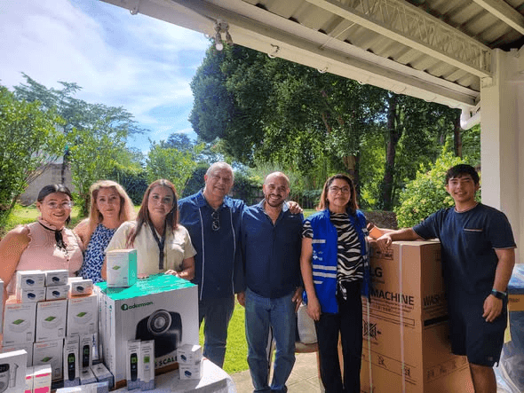 A group portrait beside donated medical equipment and washing machines